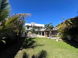 A modern building with a flat roof, surrounded by a well-maintained lawn and various tropical plants.