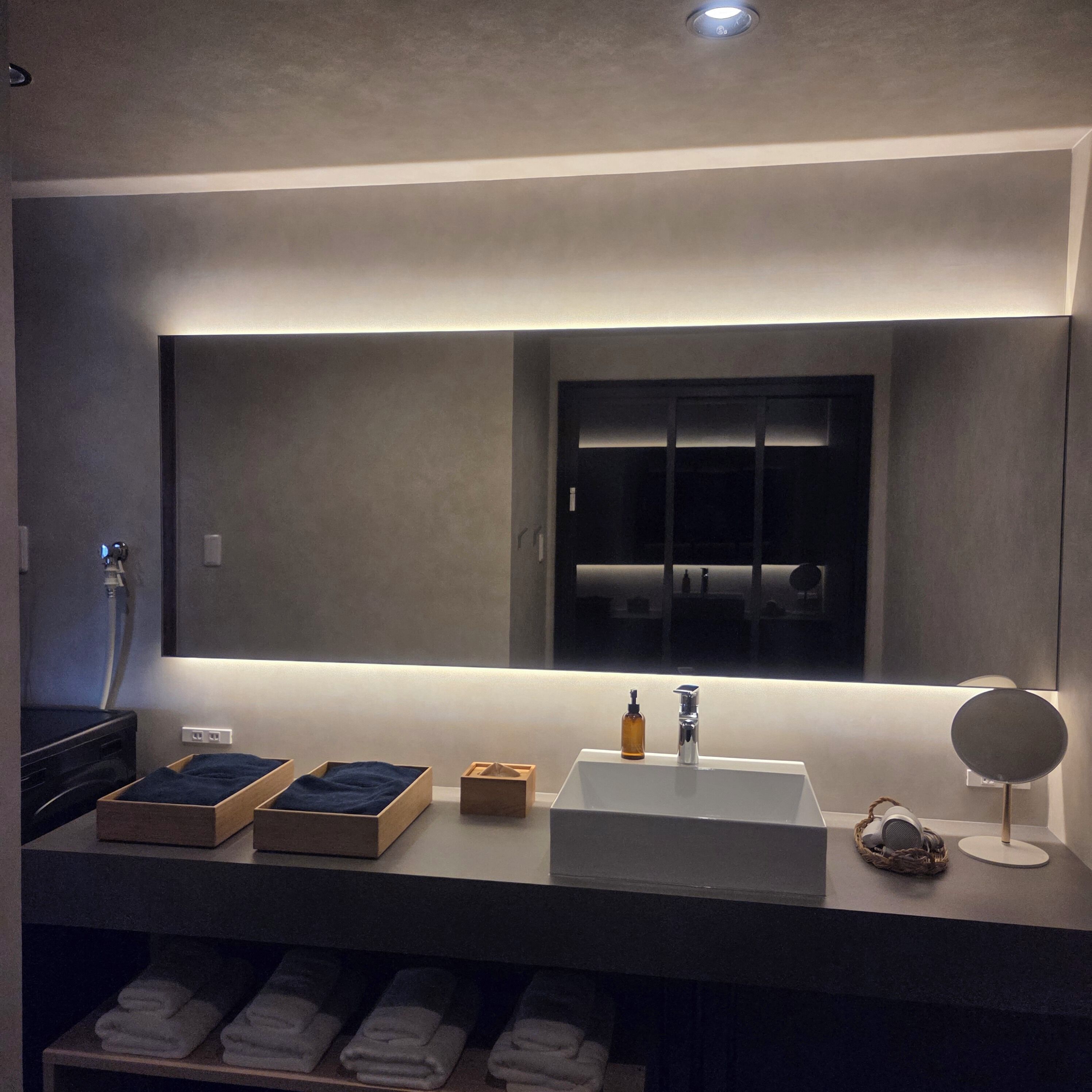 A modern bathroom with a large mirror, a sink, and a towel rack.