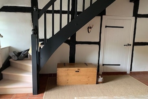 Eine Treppe mit schwarzen Spindeln, eine weiße Tür mit schwarzem Griff und eine Holzkiste auf dem Boden.