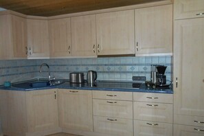 Una cocina con armarios de madera clara, encimera azul y salpicadero de azulejos.