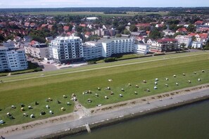 Vista aérea de uma área residencial com edifícios de apartamentos modernos, um amplo campo verde com tendas e um rio.