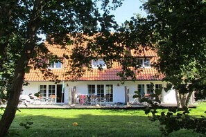 Ein zweistöckiges Gebäude mit roten Ziegeldach, großen Fenstern und einer überdachten Terrasse.