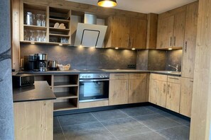 Eine moderne Küche mit Holzausstattung, einem Einbauofen und einer Kaffeemaschine.