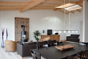 Ein modernes Wohnzimmer mit Kamin, Sofa, Esstisch und Fernseher.