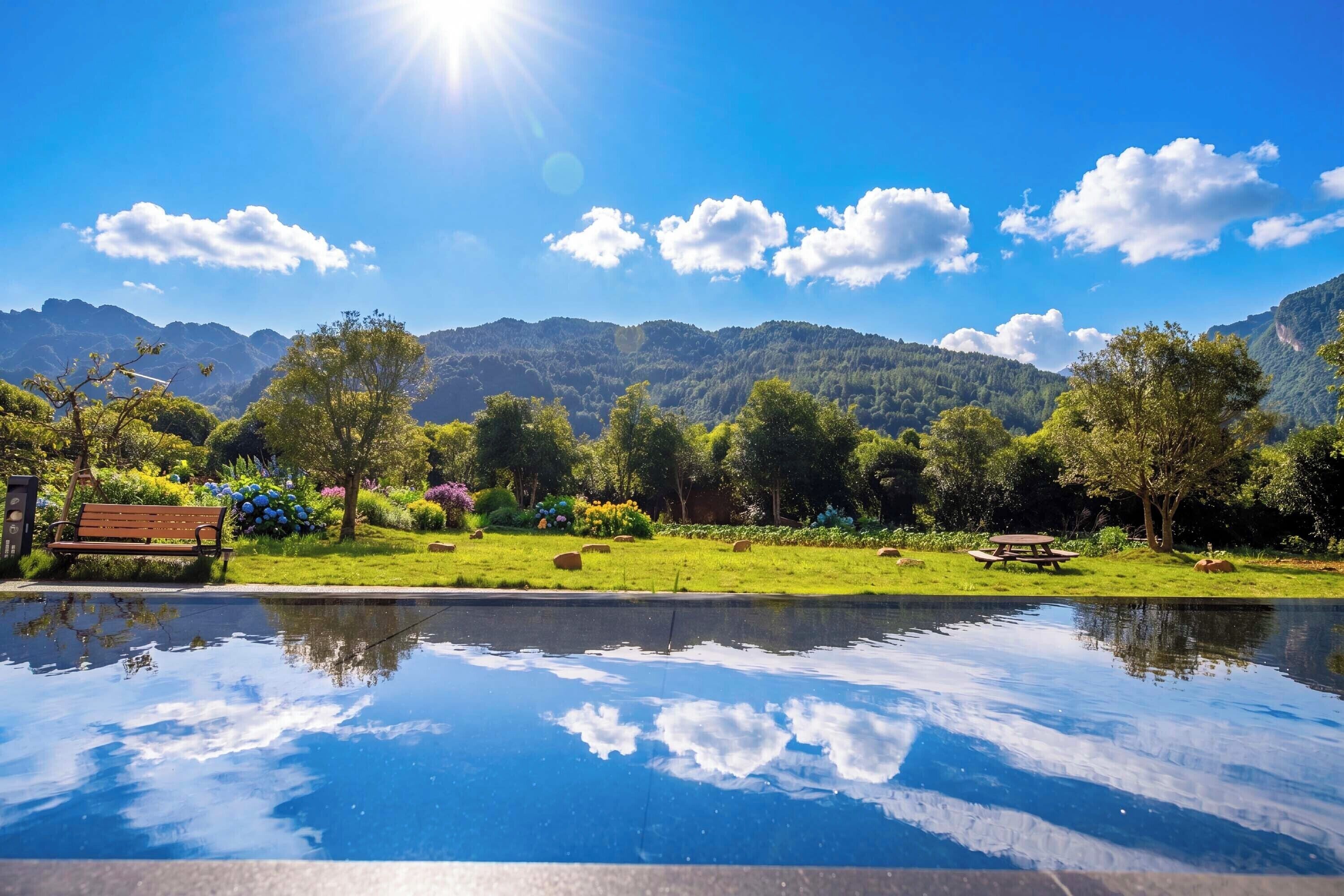 Un paisaje sereno con un estanque reflectante, bancos y una mesa de picnic.
