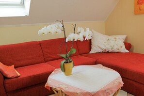 Ein rotes Sofa mit einem kleinen Tisch und einer Topf-Orchidee.
