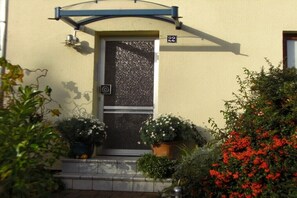 A building with a numbered door, a small porch with potted plants, and a metal awning above the door. - Holiday apartment in Kiel with swimming pool (Kiel)