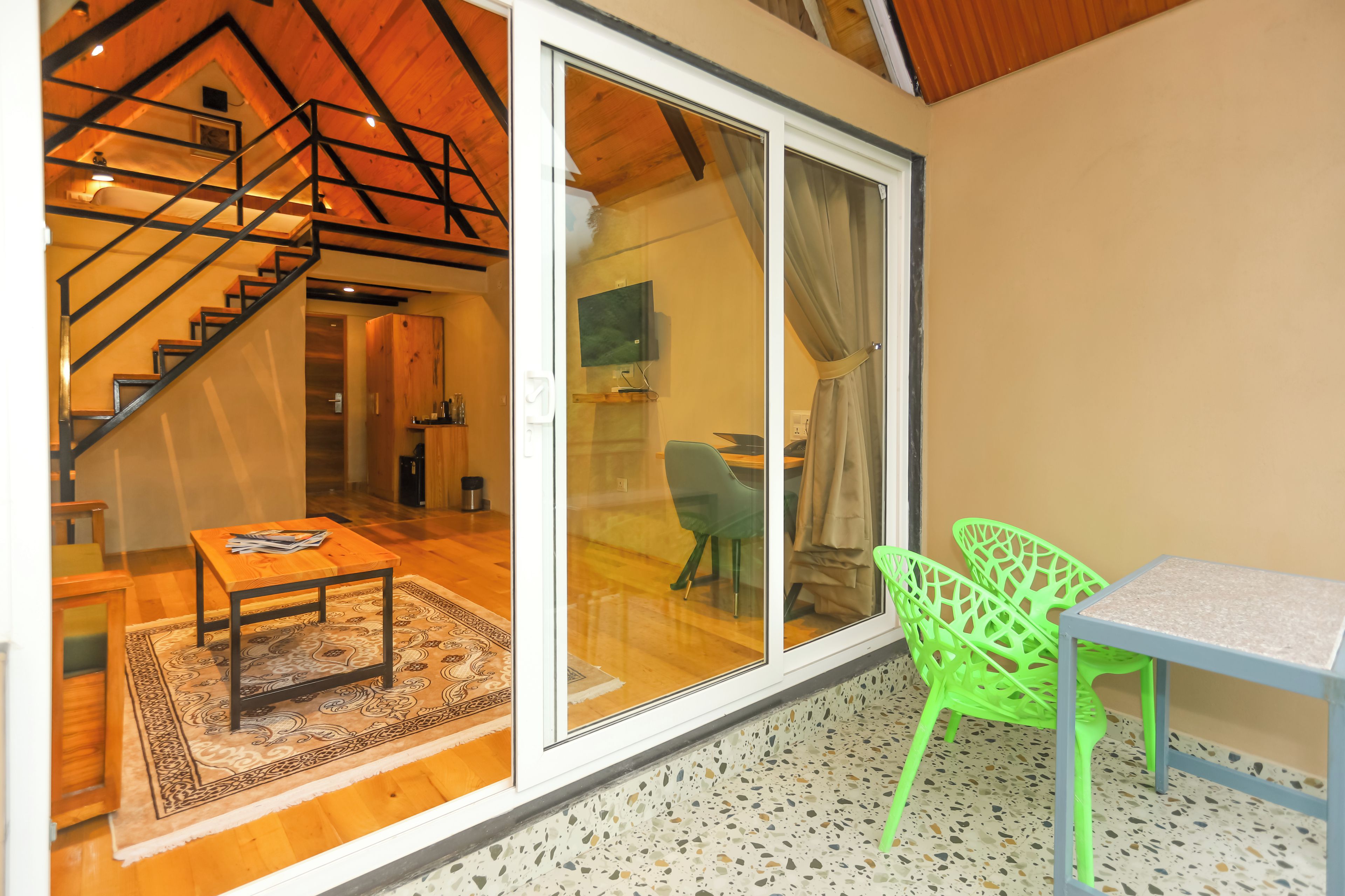 A modern interior with a wooden staircase, a sliding glass door leading to a balcony, and a dining area with a table and chairs.