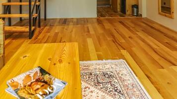 A modern interior with a wooden ceiling, a staircase with metal railings, and a dining area with a table and chairs.