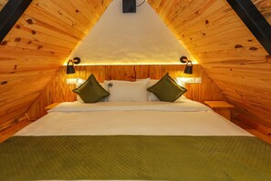 Een kamer met een driehoekige vorm, een bed, twee wandlampen en een stopcontact.