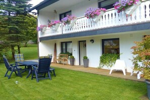 A two-story building with a balcony, outdoor seating, and potted plants. - Country House at the Linden Tree (Winterberg)