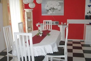 Ein Essbereich mit roter Wand, einem weißen Tisch und weißen Stühlen.