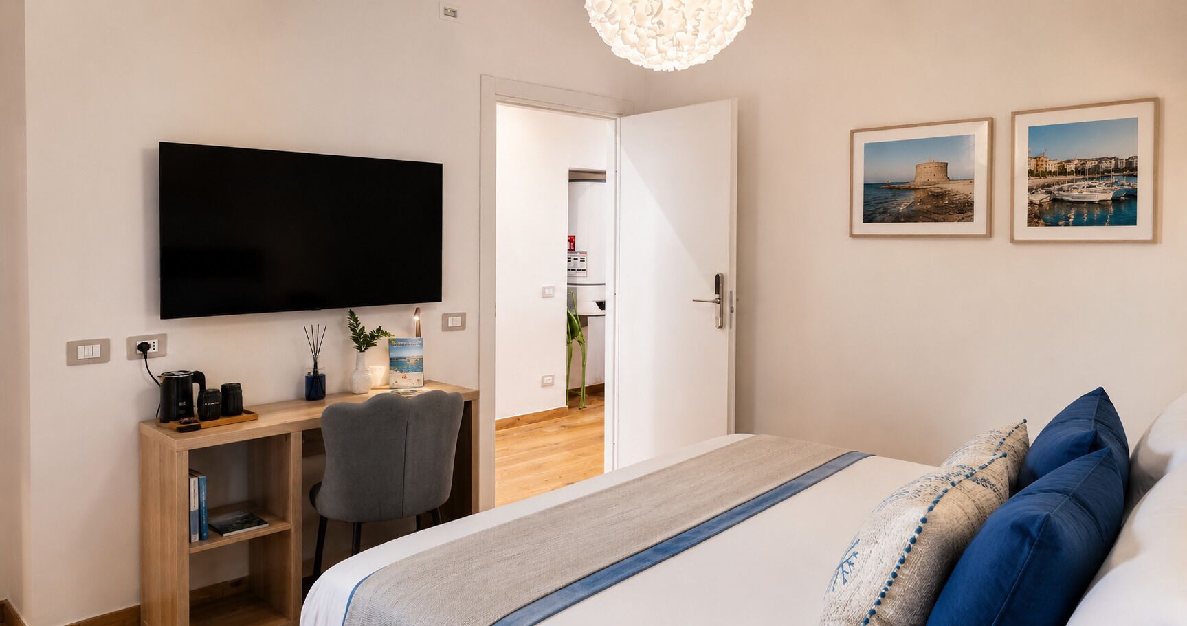 Un dormitorio con una cama, un escritorio con silla, un televisor y dos cuadros en la pared.