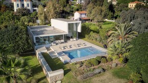 Una casa moderna con piscina, rodeada de exuberante vegetación y palmeras.