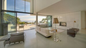 Una sala de estar moderna con un gran ventanal, un sofá, una mesa de centro, un televisor y una lámpara.