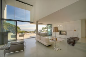 A modern living room with a large window, a sofa, a coffee table, a TV, and a lamp. - Other (Vallauris)