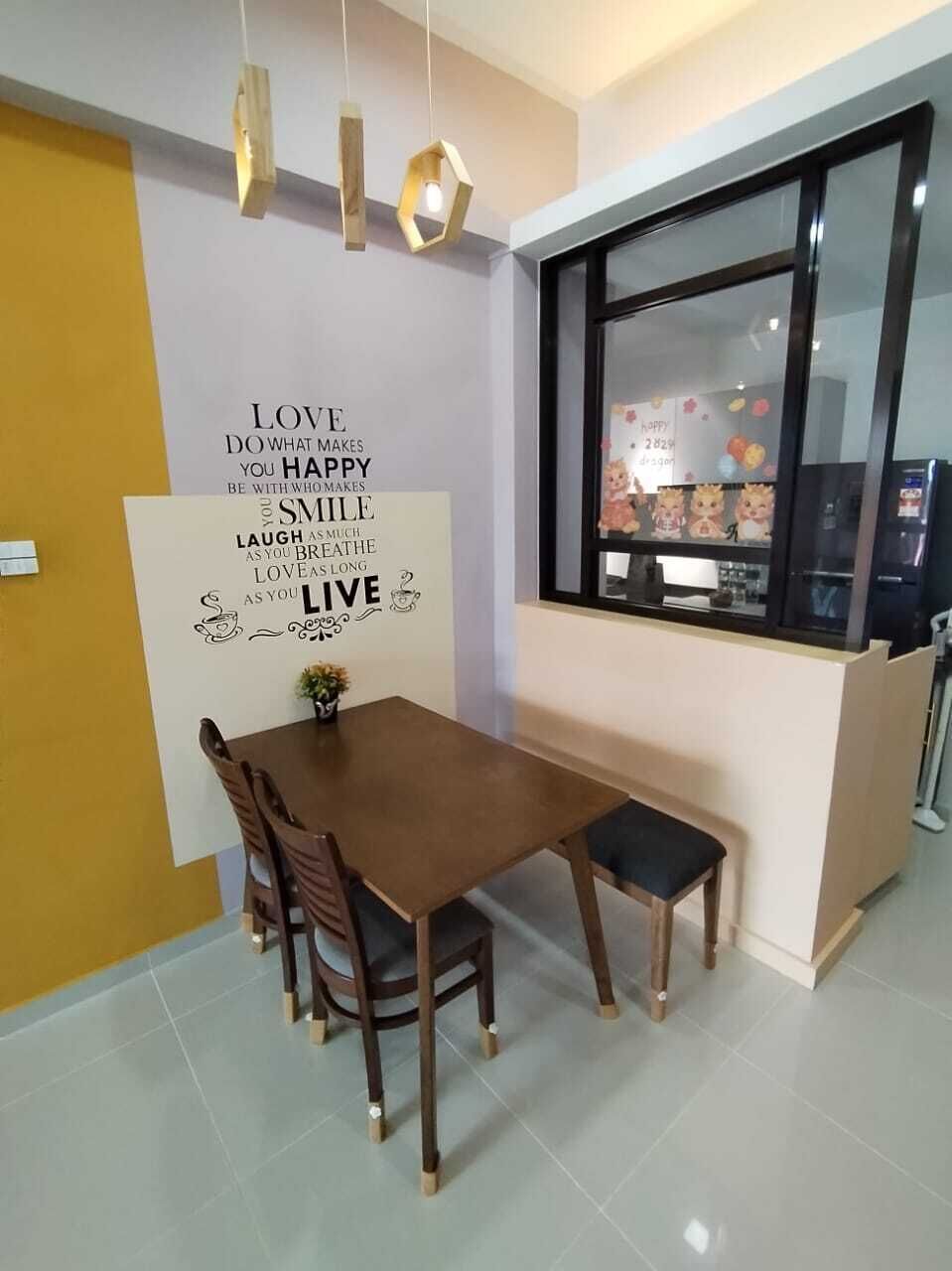 A dining area with a wooden table and chairs, a wall with a motivational quote, a window with a view of a refrigerator and a shelf with items, and a hanging light fixture.