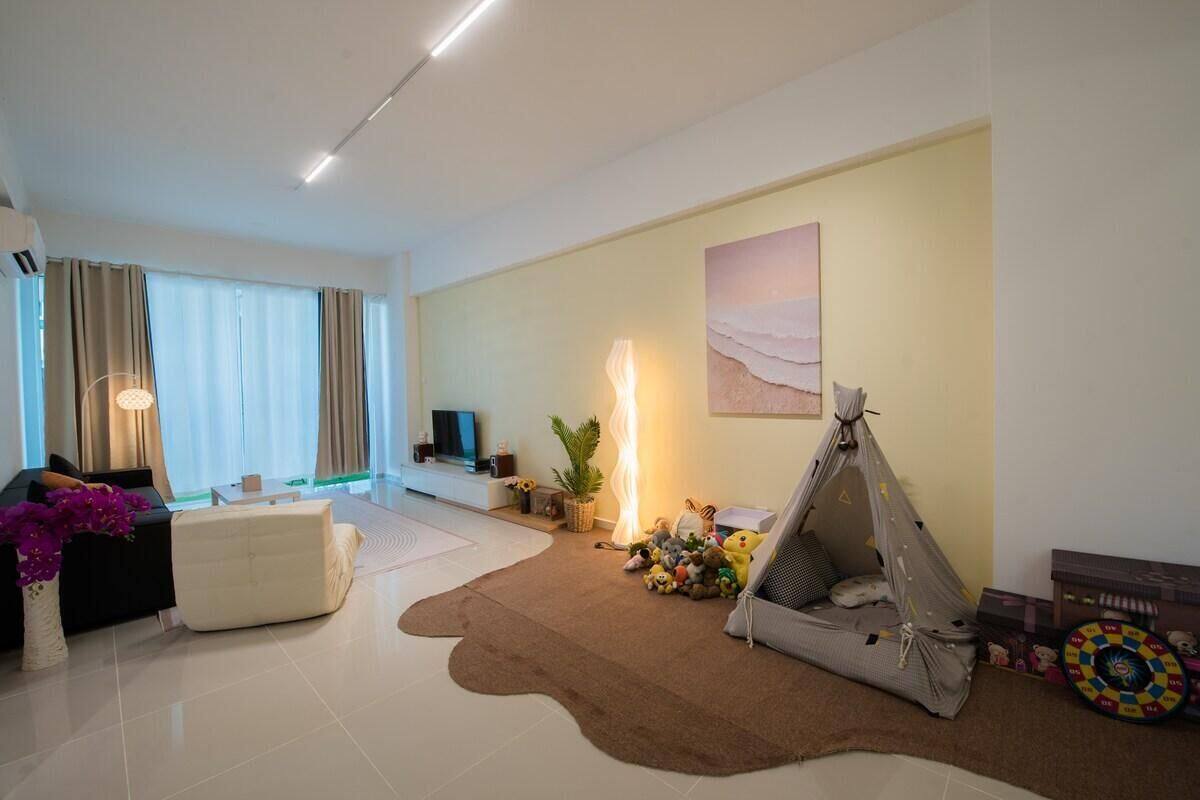 A living room with a sofa, a coffee table, a lamp, a tent, and a dartboard.