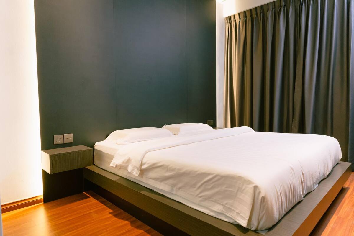 A modern hotel room with a bed, bedside table, and curtains.