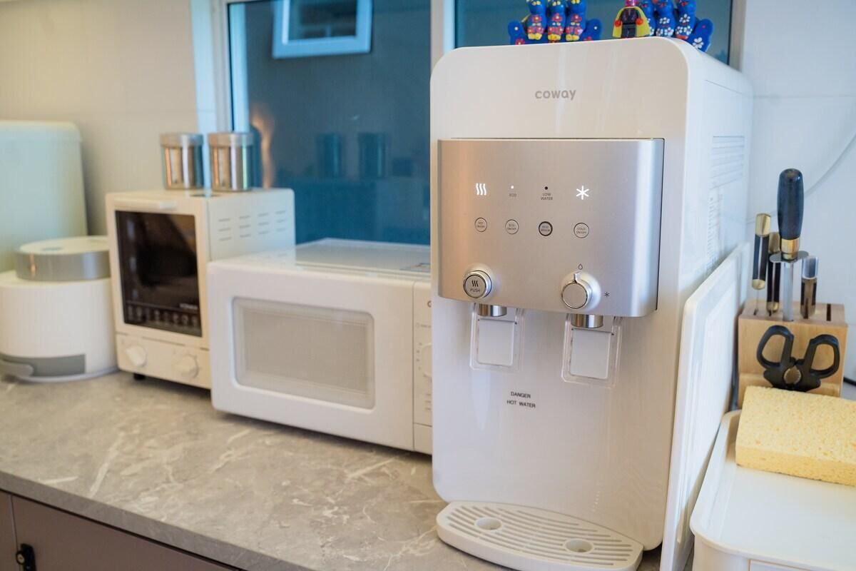 A kitchen with a water dispenser, a microwave, and a toaster.