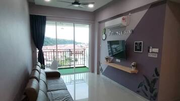Un salon avec un canapé, un téléviseur et un balcon offrant une vue agréable.