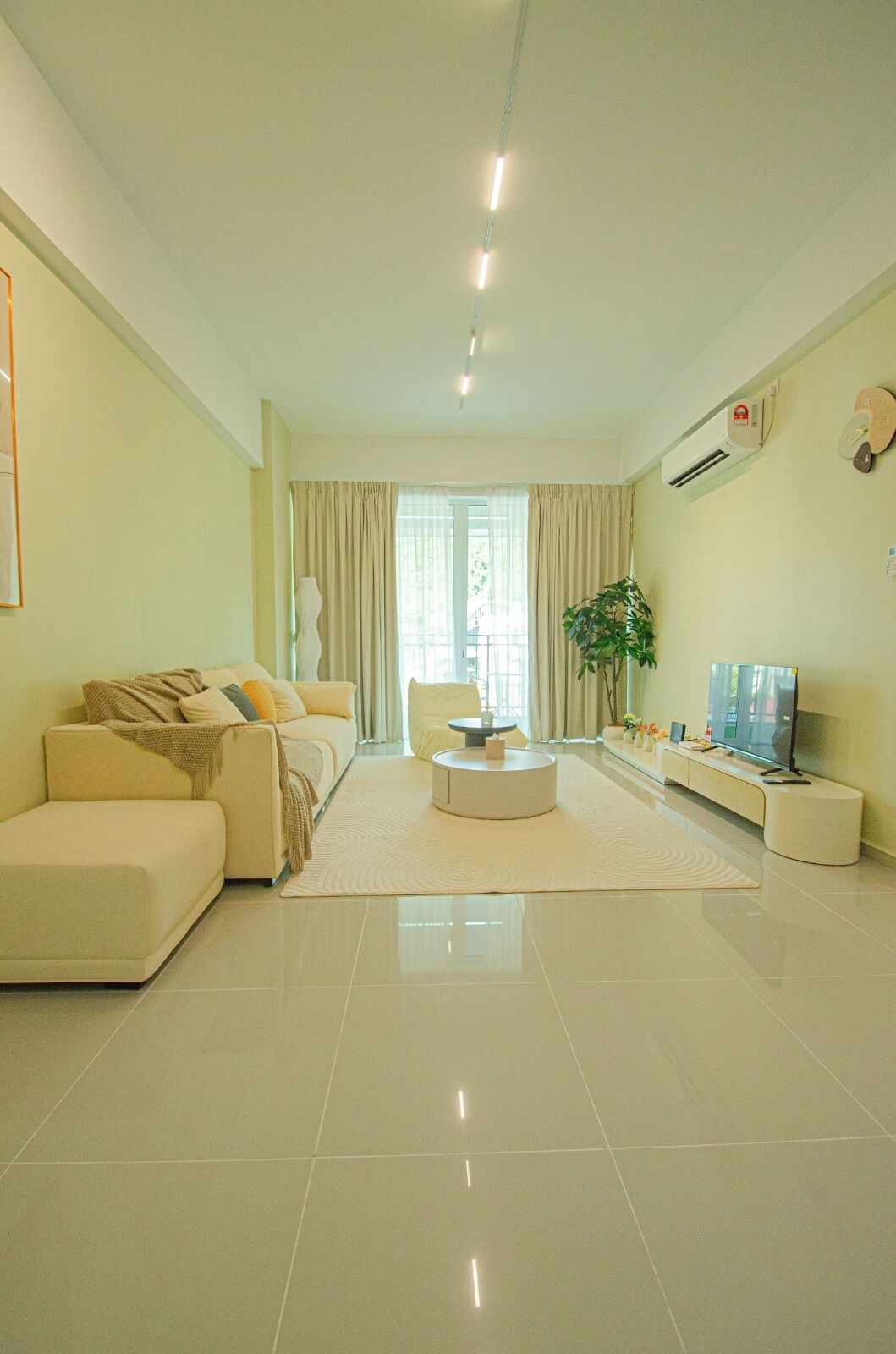 A modern living room with a sofa, a coffee table, a TV, and a plant.