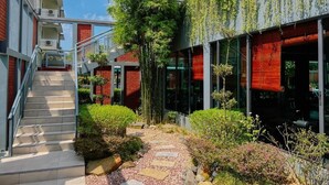 Un edificio moderno con una escalera, puertas de vidrio y un jardín.