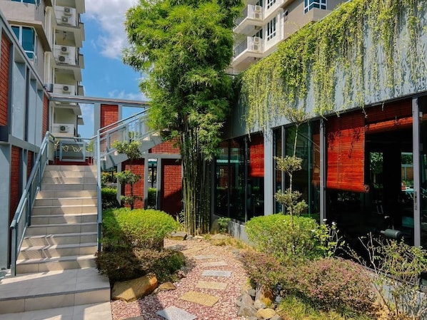 A modern building with a staircase, glass doors, and a garden area.