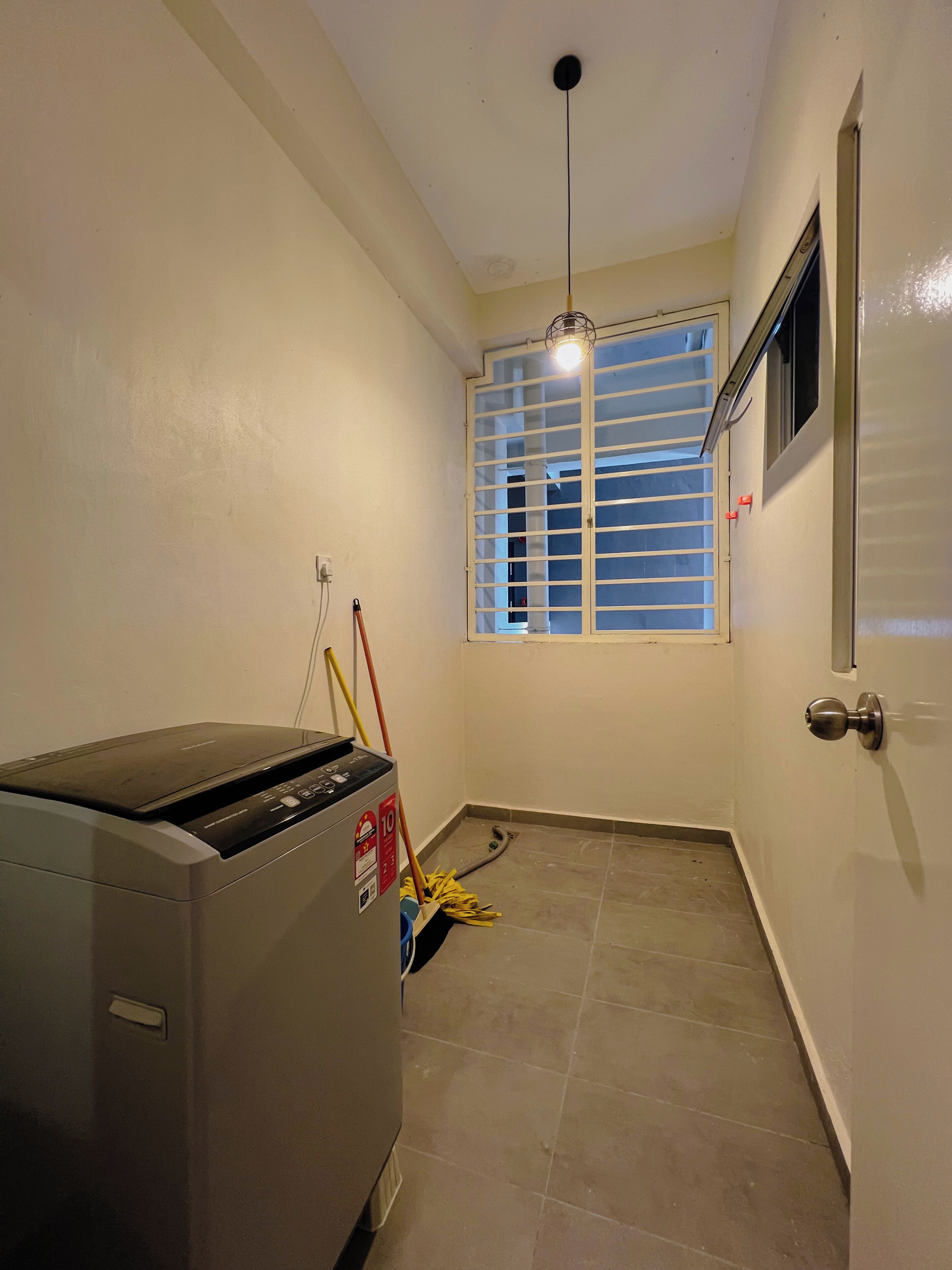A laundry area with a washing machine, a window with blinds, a door, and a ceiling light.