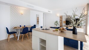 Une cuisine moderne avec un îlot central en bois, des meubles blancs et des chaises bleues.