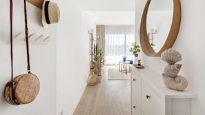 Ein modernes Interieur mit Holzboden, einer weißen Wand mit großem Spiegel und einer Pflanze im Hintergrund.
