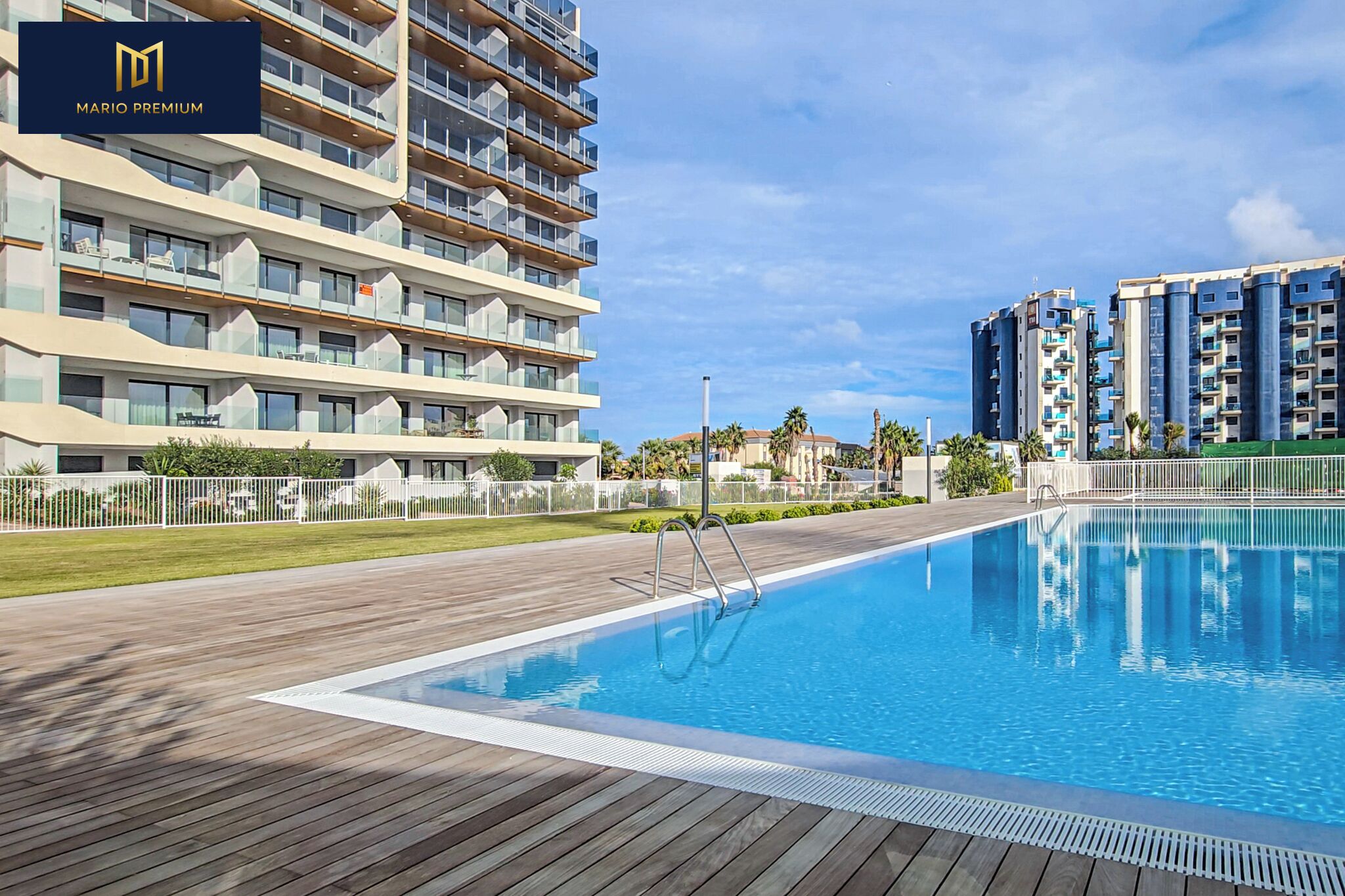 Un hotel moderno con piscina, varios balcones y un espacio exterior bien cuidado.