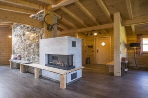 A log cabin interior with a stone wall, wooden beams, a fireplace, and a bench. - Cabin in Wörgl with swimming pool (Wörgl)