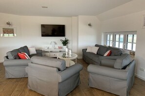 A living room with grey sofas, a white coffee table, a flat-screen TV, and a window with blinds. - Holiday home in Mellnitz with swimming pool (Mellnitz)