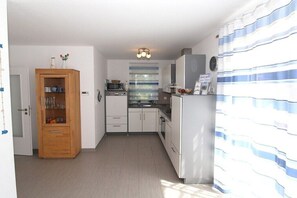 Eine kleine Küche mit weißen Schränken, einem Holzschrank und einem Kühlschrank.