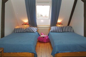 Ein Zimmer mit zwei Betten, einem Fenster und einer Heizung.