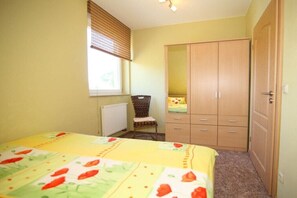 A bedroom with a bed, a chair, a wardrobe, and a window with blinds. - At the Forest Spring - To the Stork Tower (Angermünde)
