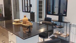 A modern kitchen with a large island, black bar stools, and pendant lighting.
