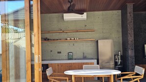 An outdoor kitchen area with a dining table and chairs, a ceiling fan, and a stone wall.