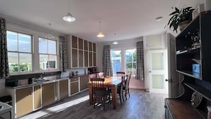 A modern kitchen with a dining area, large windows, and a view of the outdoors. - Cliff Top Homestead - great for couples, friends, families and large groups (Ōhingaiti)
