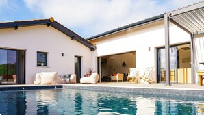Ein modernes Haus mit Schwimmbad, Sitzgelegenheiten im Freien und einer Garage.