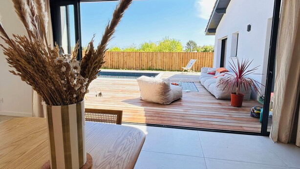 Ein modernes Wohnzimmer mit einem großen Schiebeglasfenster, das auf eine Terrasse im Freien führt.