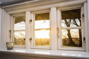 Ein Fenster mit drei Teilen, jedes mit einem Messinggriff, und ein kleiner Korb auf dem Sims.