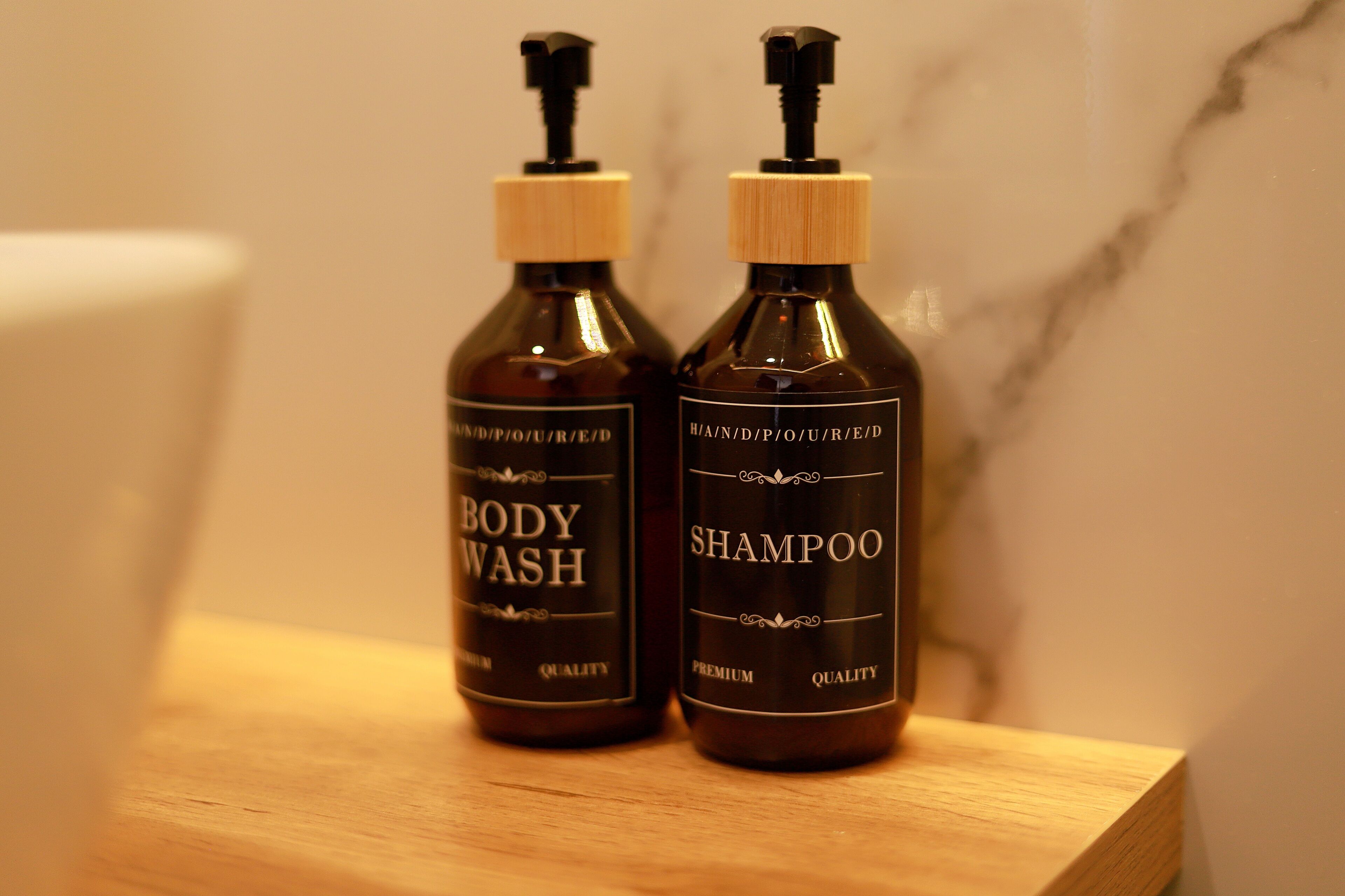 Twee flessen douche- en shampoo op een houten ondergrond.