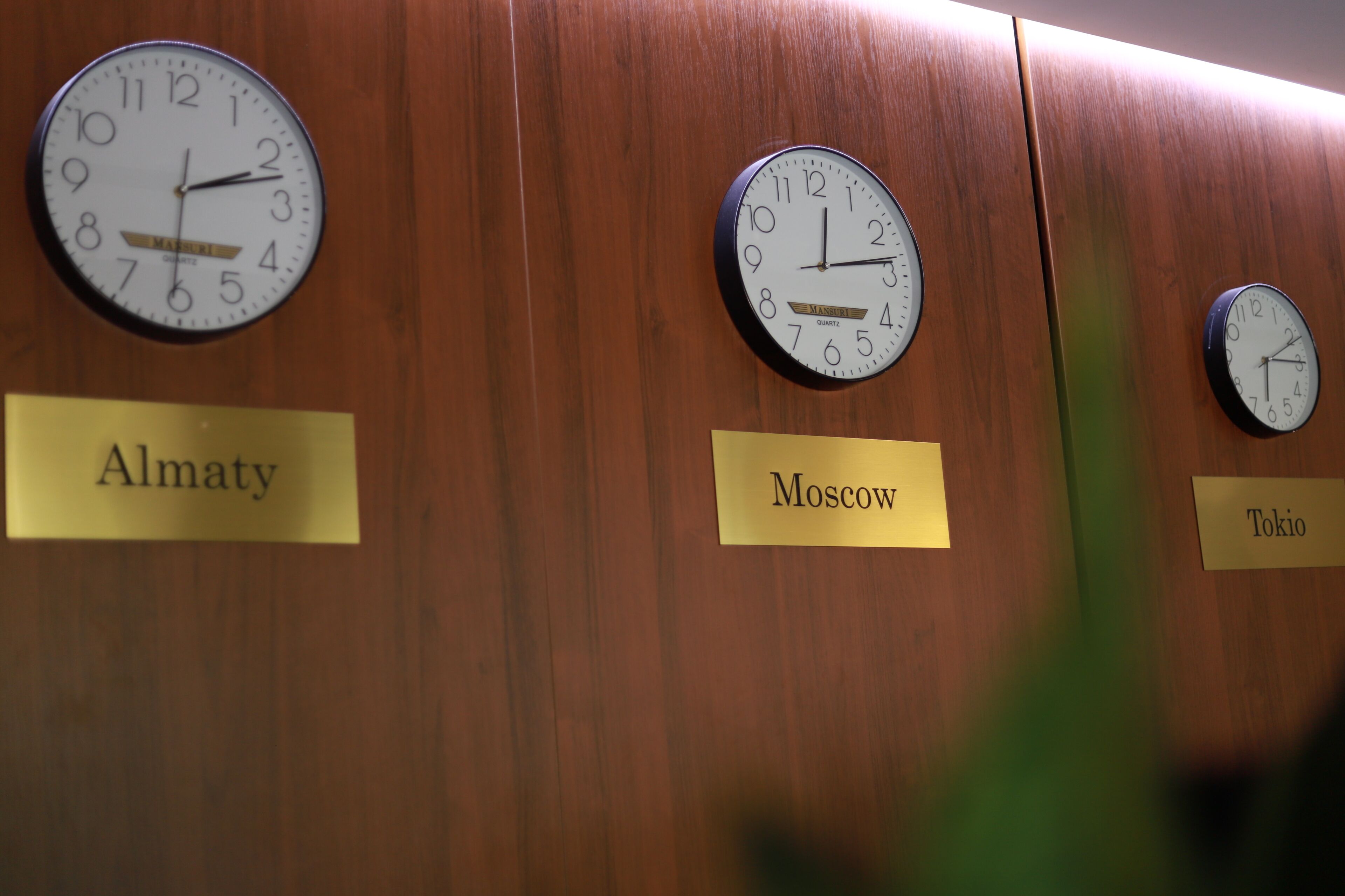 Clocks labeled with city names on a wooden wall.