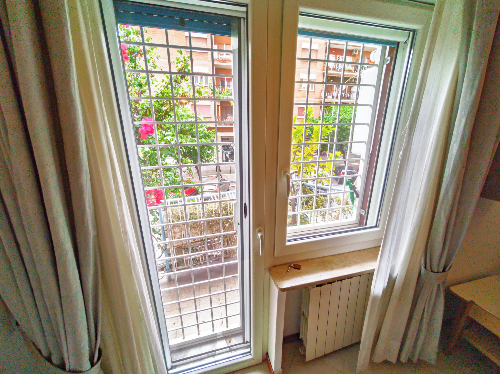 Una habitación con dos ventanas, un radiador y una puerta.
