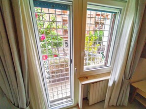 A room with two windows, a radiator, and a door. - Casa Del Colle (Roma)