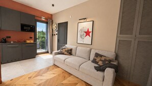 Ein modernes Wohnzimmer mit einer Couch, einer Küchenzeile und einem großen Fenster.