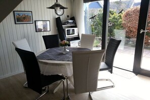 Ein Essbereich mit Tisch, Stühlen, einer Uhr und Blick ins Freie.