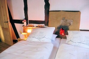 Ein Schlafzimmer mit zwei Betten, einem Nachttisch mit Kerzen und einem rustikalen Kopfteil.